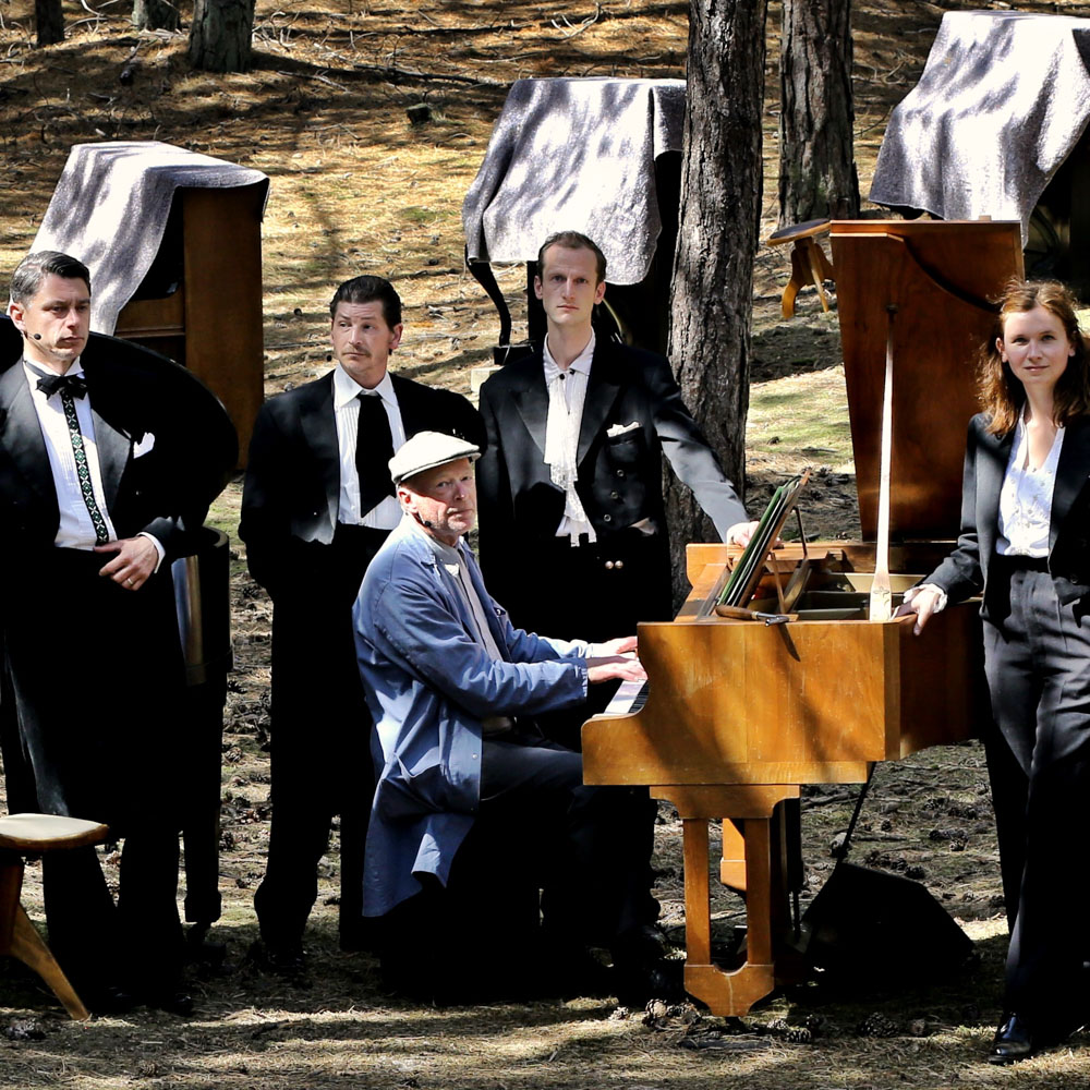 Een groepsfoto van vijf muzikanten met meerdere piano's in beeld