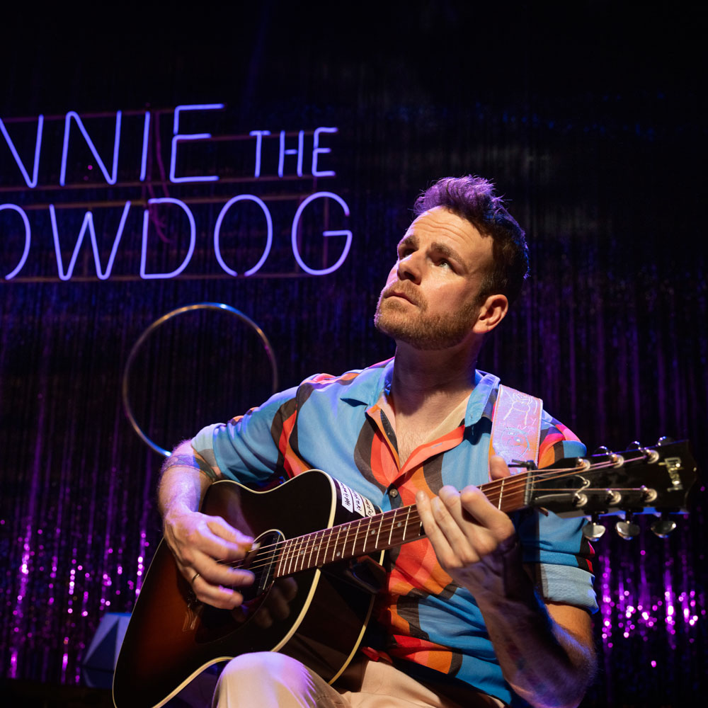 Henry van Loon zittend met een gitaar