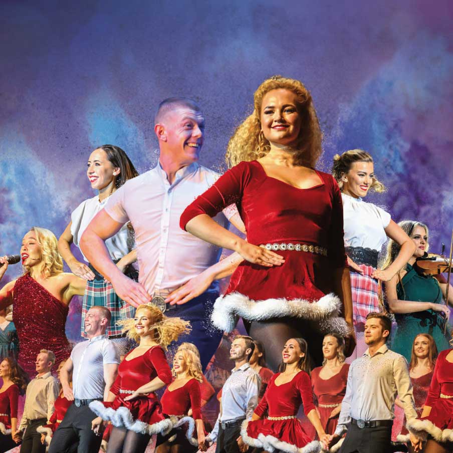 Voorstellingsbeeld van Rhythm of the Dance: 'Optreden van zangers en dansers in feestelijke kleding met een kerstthema op een kleurrijk verlicht podium.