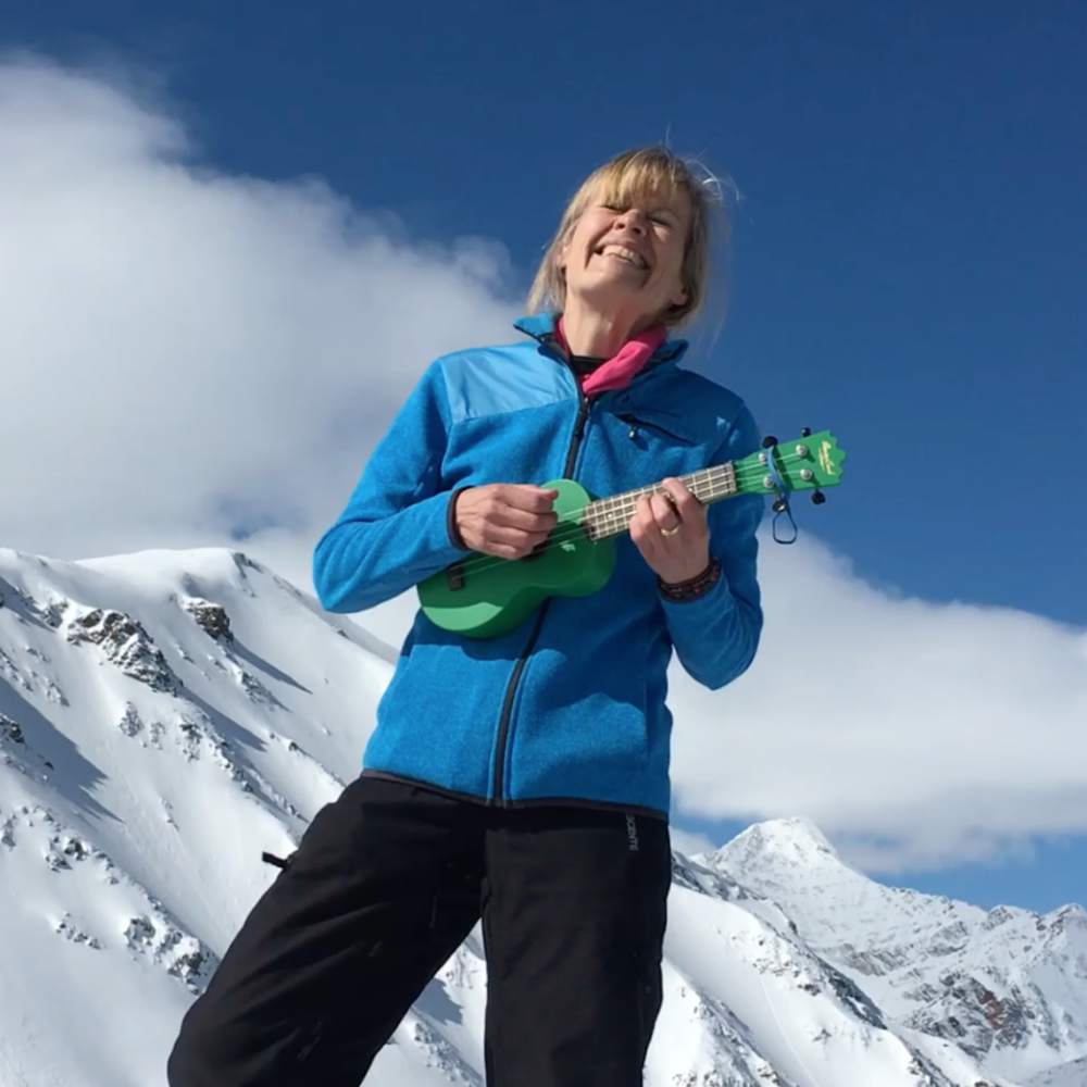 Voorstellingsbeeld Fay Lovsky: een vrouw die een ukelele speelt in de sneeuw tegen een achtergrond van bergtoppen.