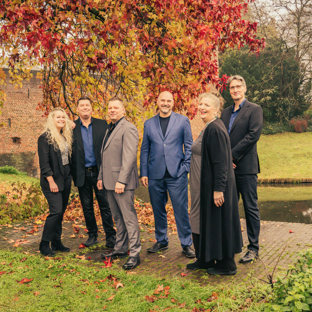 Alexander Broussard & Friends poseren lachend buiten bij herfstbladeren en een gracht.