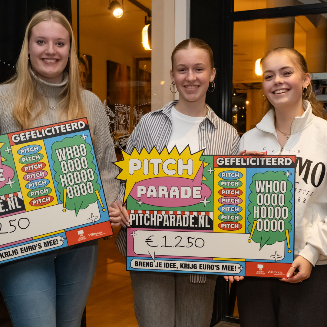 Glimlachende deelnemers van pitch parade tonen hun gewonnen cheques in een sfeervolle ruimte.