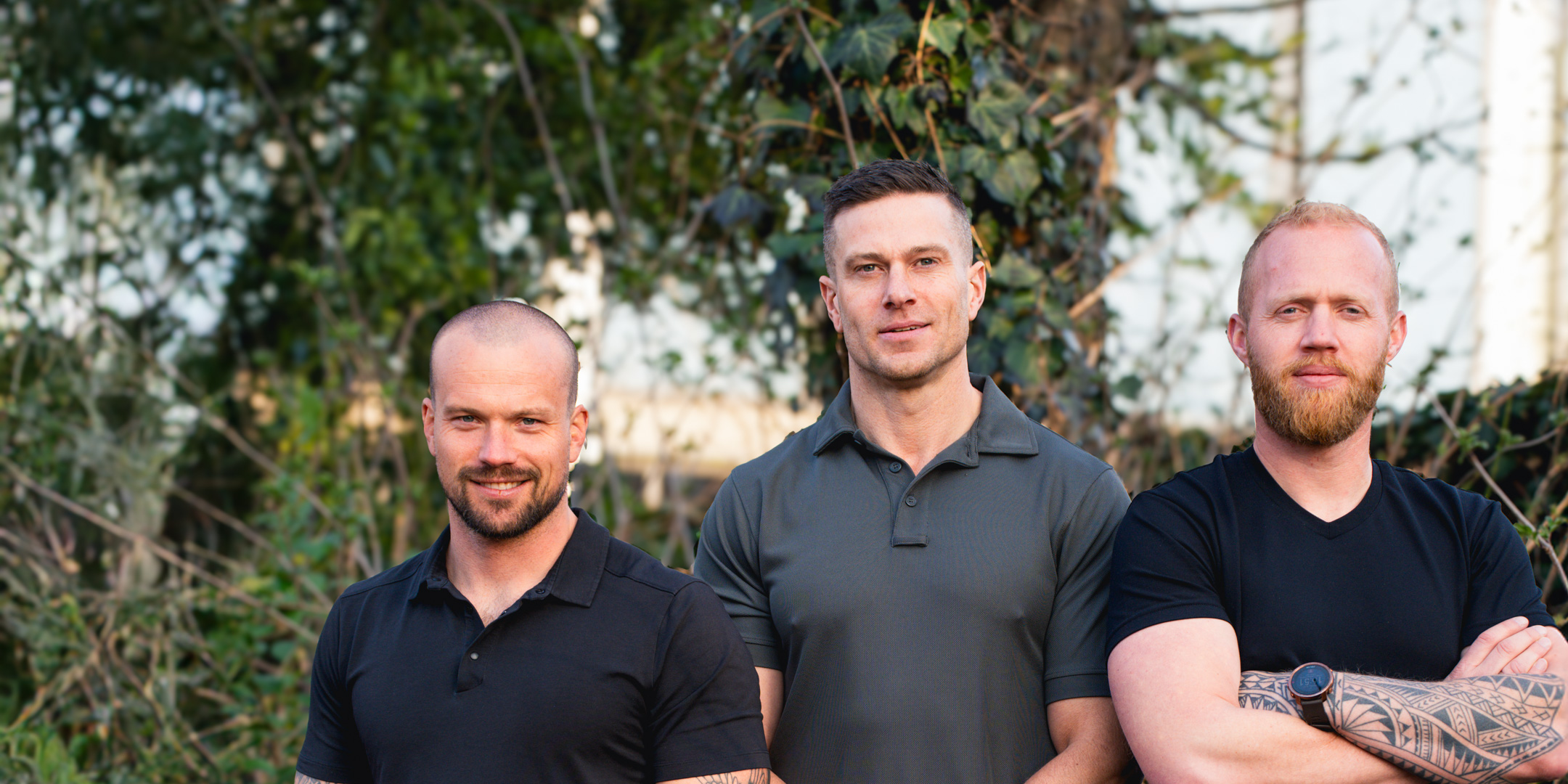 Dai, Derek en Robin in zwarte shirts staan zij aan zij in natuurlijke setting.