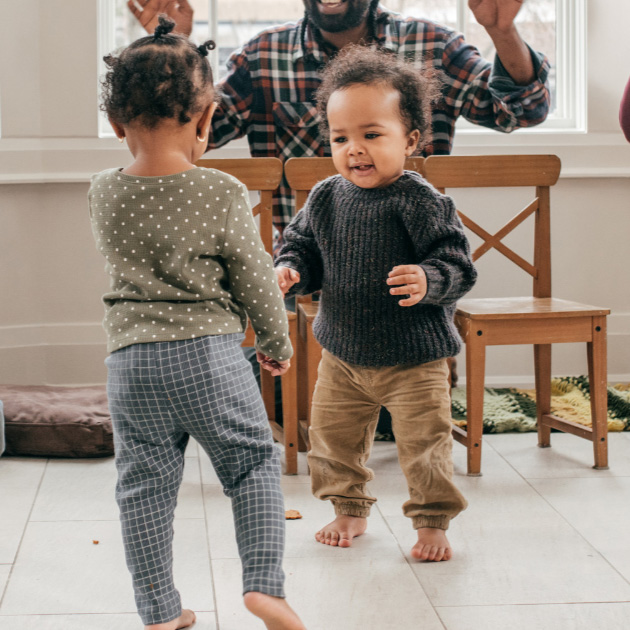 Peuters dansen in een lichte ruimte, ouders moedigen hen enthousiast aan.