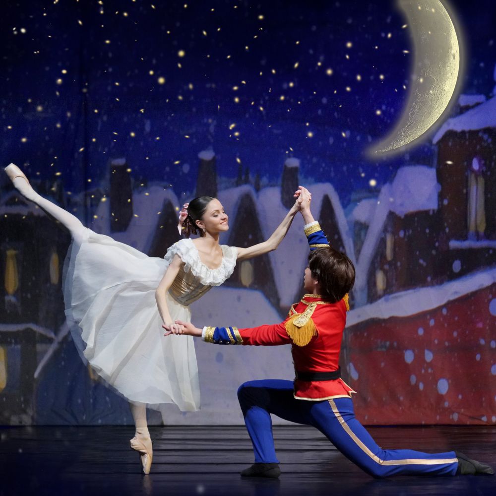 Ballerina balanceert op spitzen terwijl danser haar ondersteunt onder maanlicht