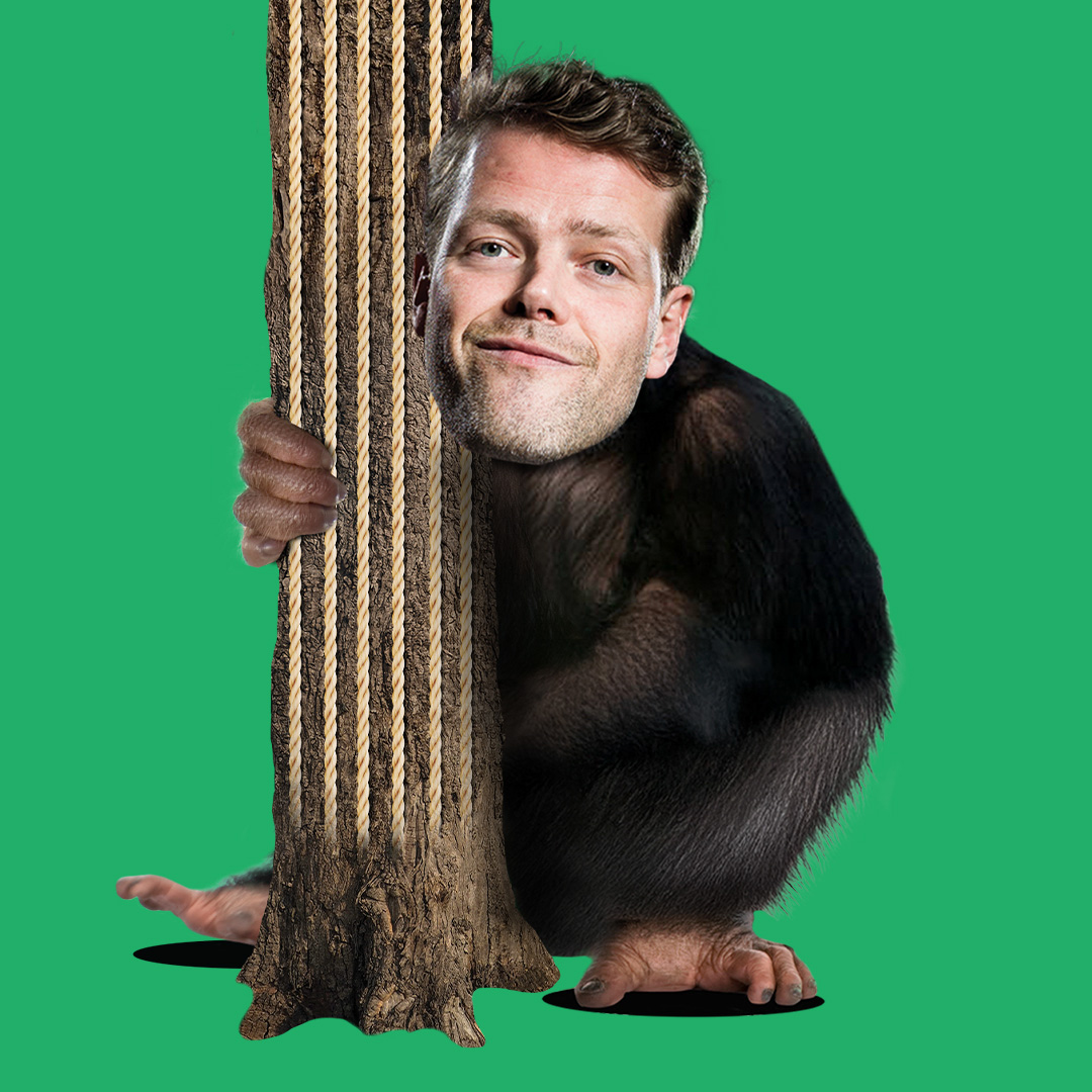 Martijn Koning met apenlichaam verstopt zich achter een boomstam met touwen op een fel groene achtergrond.