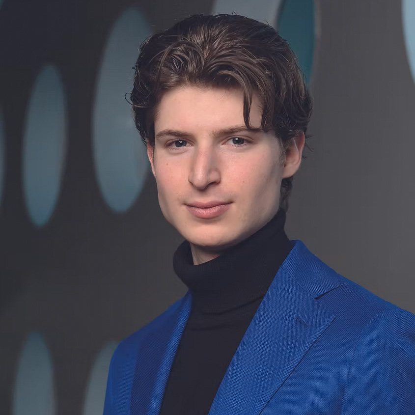 Portret van Maxim Heijmerink in blauwe blazer en zwarte coltrui.