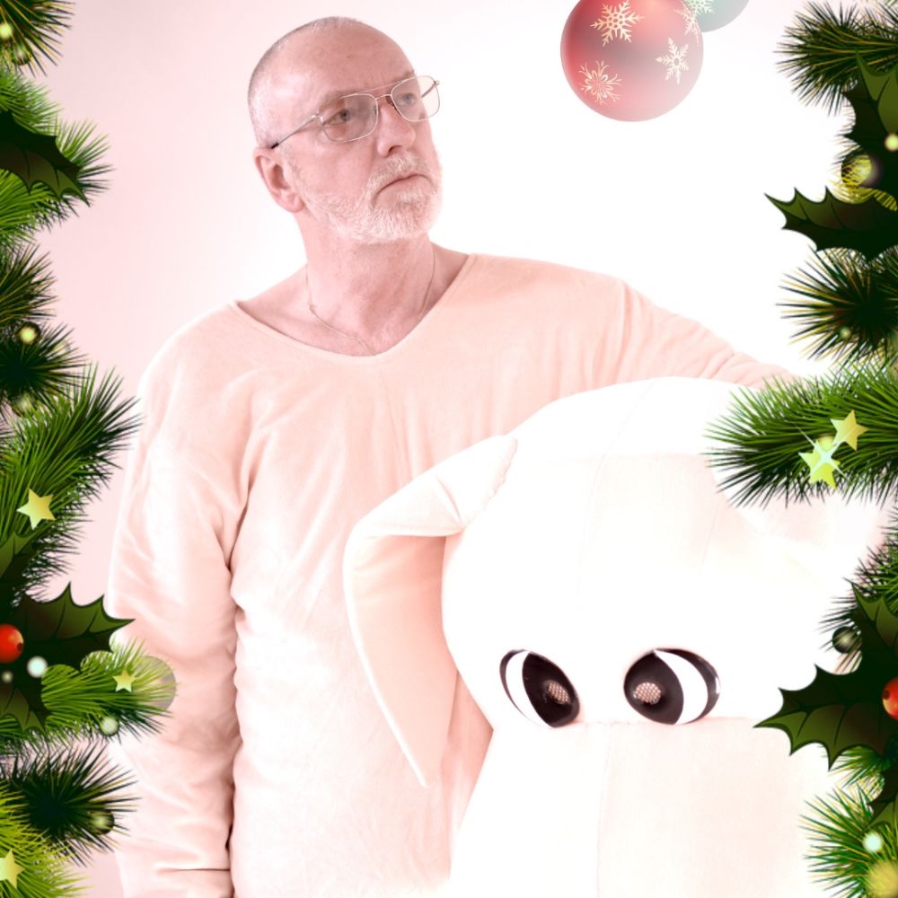Ton Kas in half licht pak met knuffelhond, omringd door kerstdecor