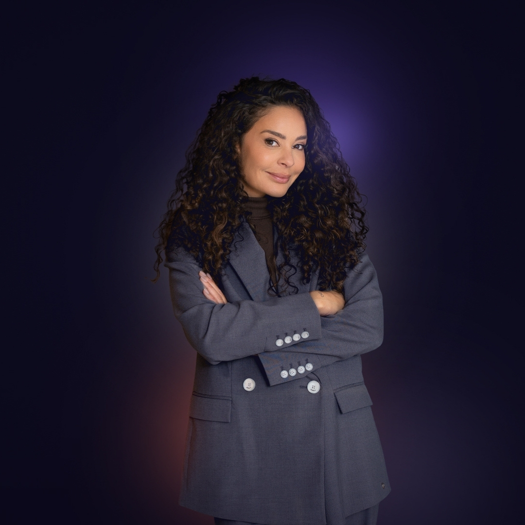 Fajah Lourens poseert in donkerblauwe jas tegen paarse achtergrond