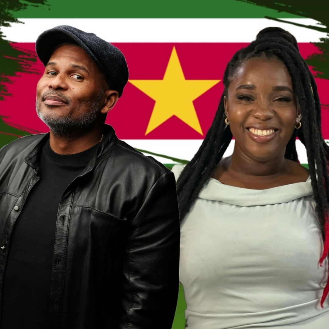 Roue en Chelle staan lachend voor een geschilderde Surinaamse vlag.