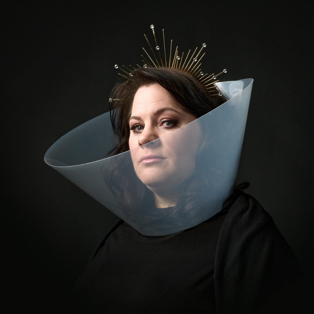 Berit Companjen kijkt recht vooruit met een transparante kraag en gouden kroon op zwart achtergrond.