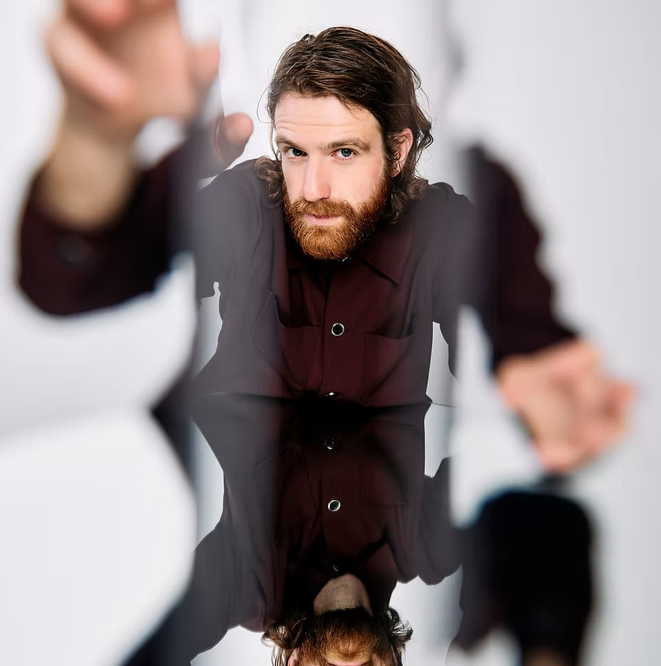 David van Rosmalen kijkt indringend in de camera, handen reiken naar voren.