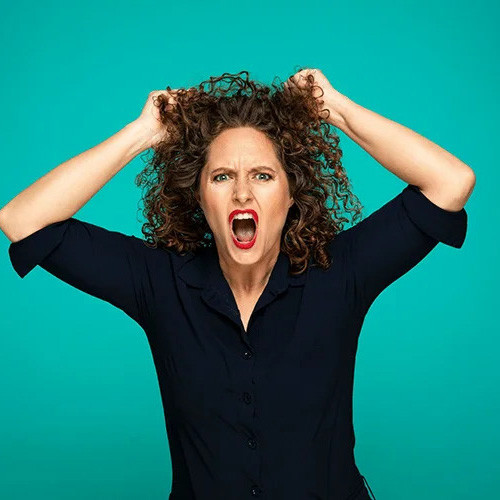 Esther van der Voort schreeuwt met handen in haar krullen tegen een felgroene achtergrond.