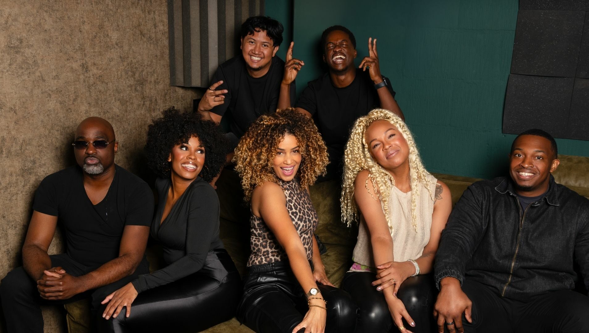 Je ziet de cast van Child of Destiny dichtbij elkaar op de bank, met brede glimlach en handgebaren.