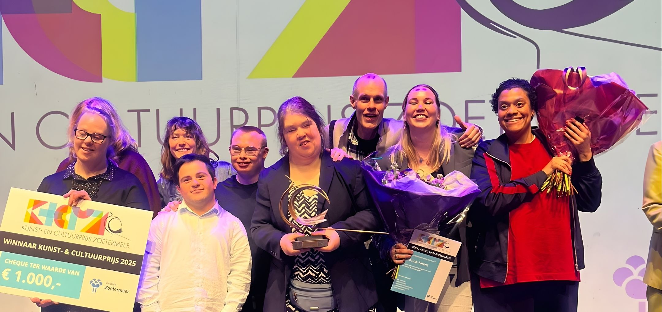 Winnaars van Kunst- en Cultuurprijs Licht op Talent staan samen op het podium met trofee en bloemen.