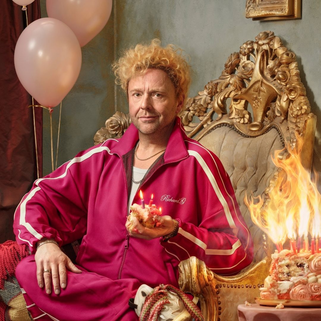 Richard Groenendijk in roze trainingspak op barokke troon, met brandende taart en ballonnen.