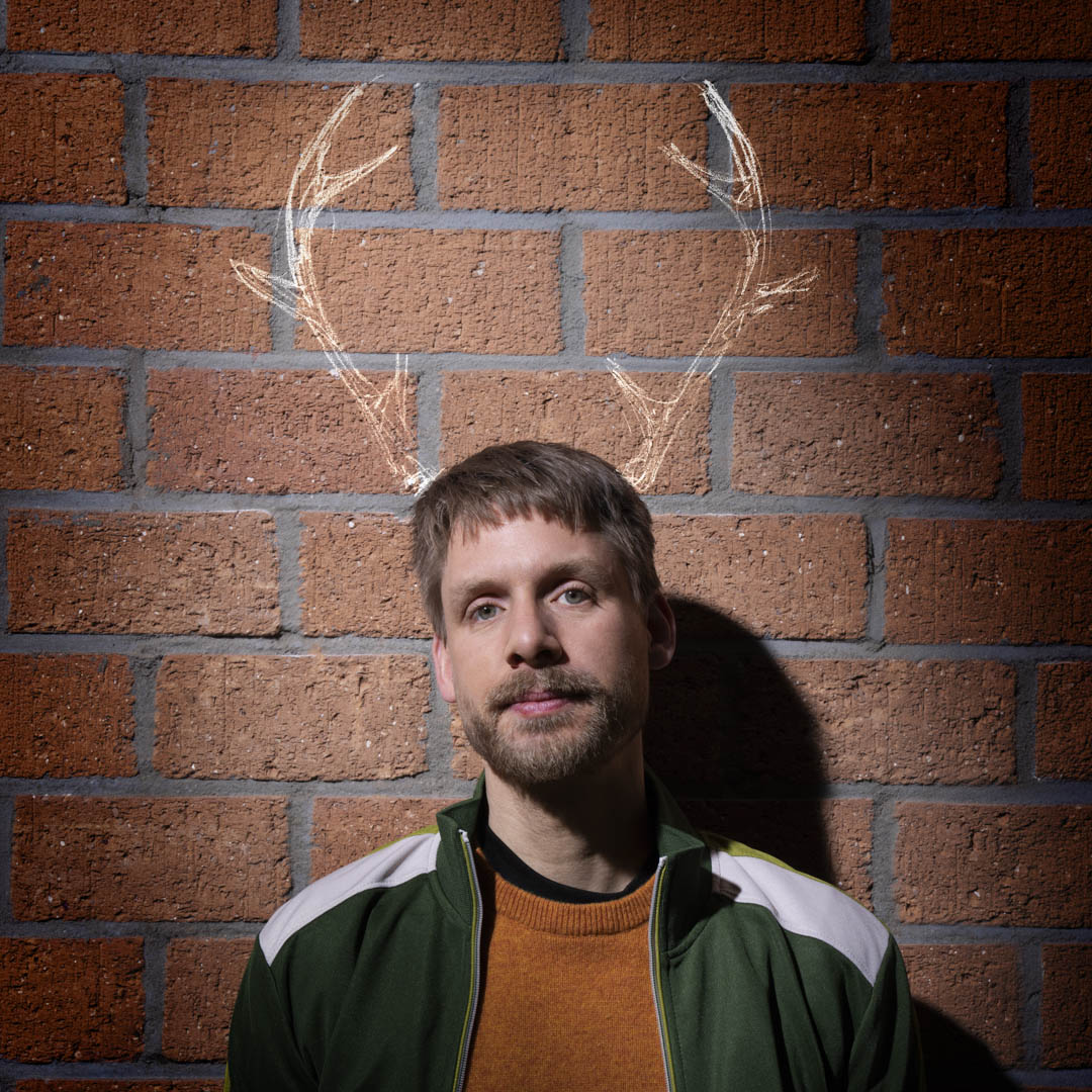 Man voor bakstenen muur met gekrijte hertentakken, verwijzend naar Baby Reindeer.