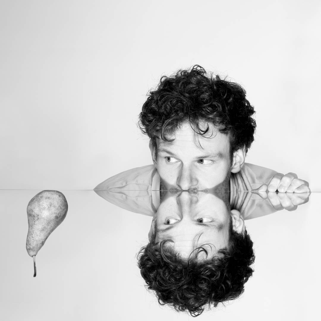 Zwart-wit portret van Bob Koomen met krullen en een peer in cabaretvoorstelling Peer.
