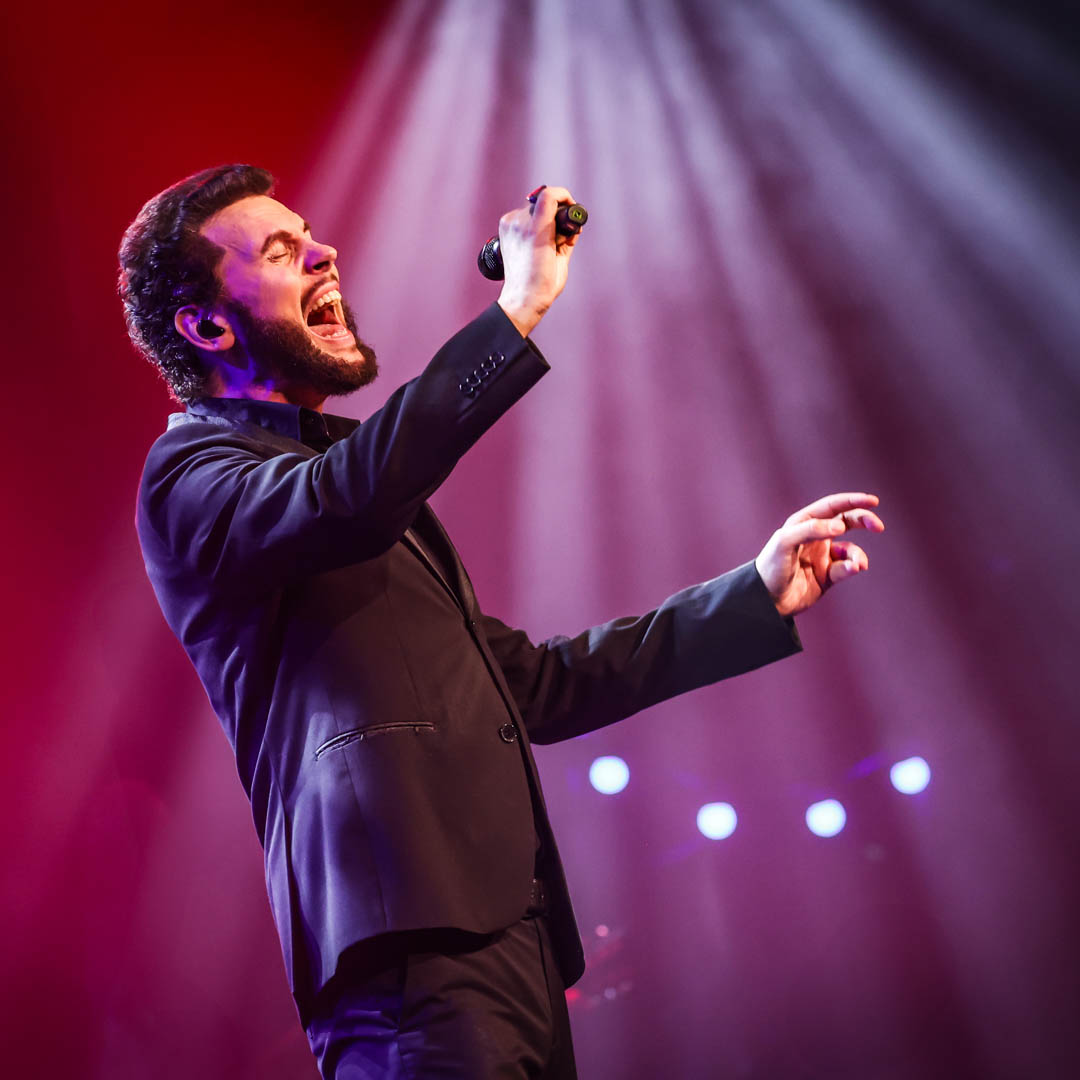 Bouke zingt in paars licht met microfoon in Elvis tribute Nieuwe Elvis show.