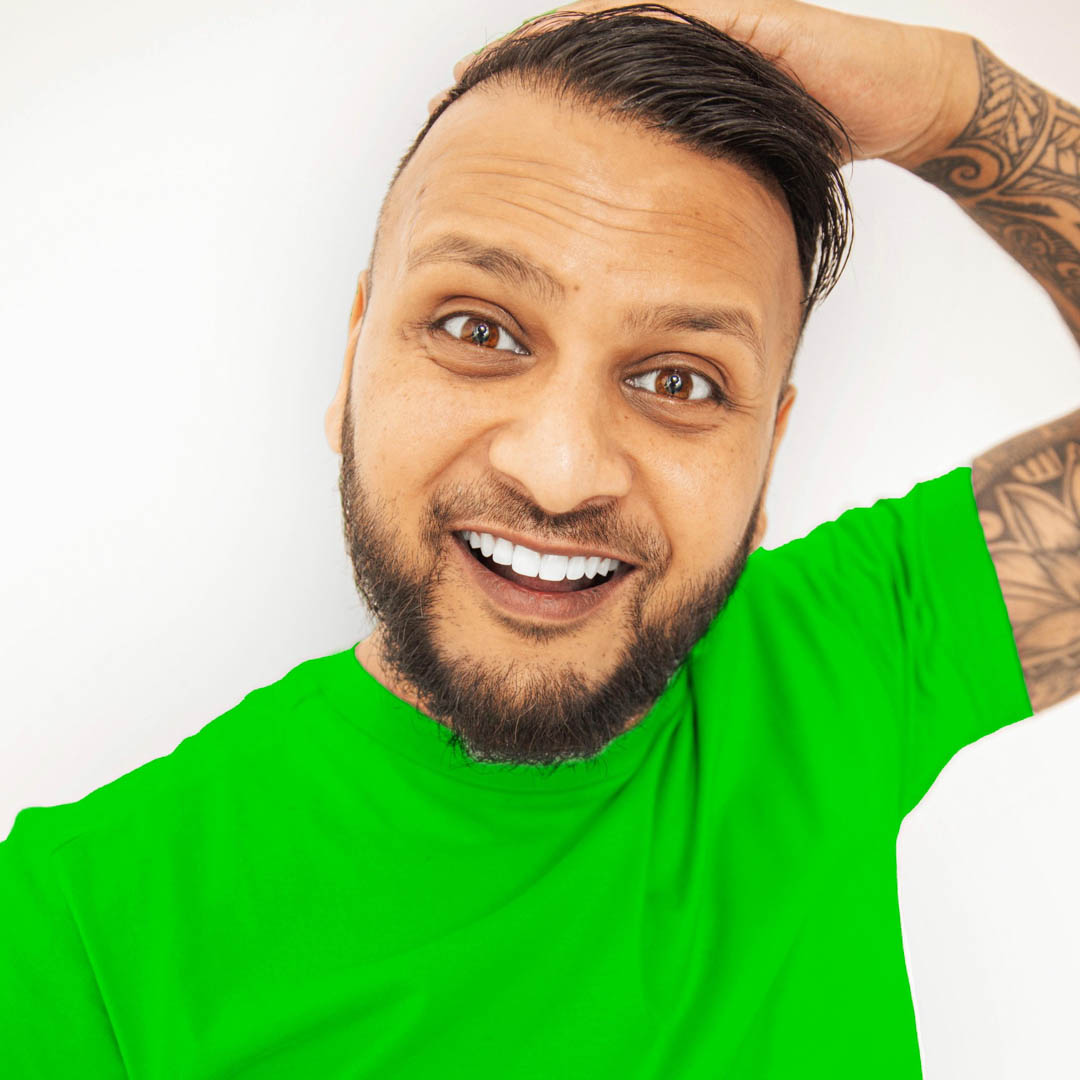 Cha Chi Versaci in groen shirt lacht voor witte achtergrond in cabaret Een arend vliegt op eenzame hoogte.