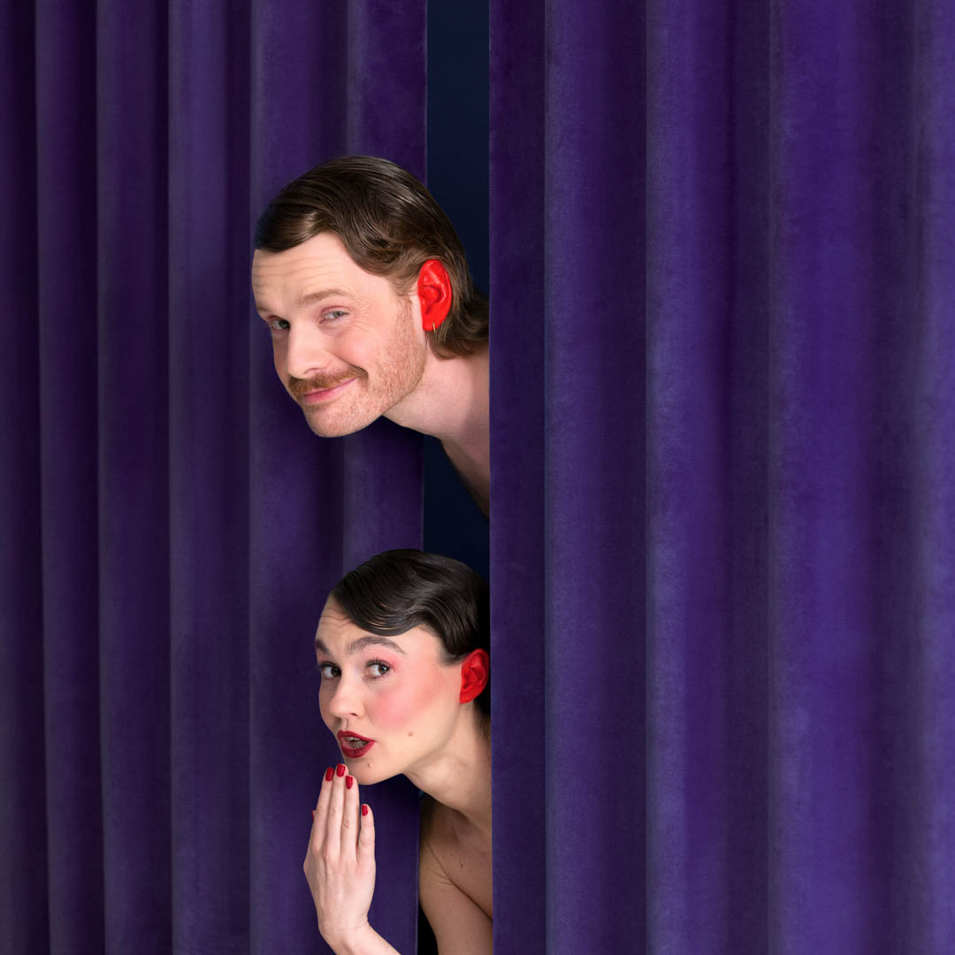 Anne en Bas kijken door paars gordijn in cabaretrevue De natte dromen revue.
