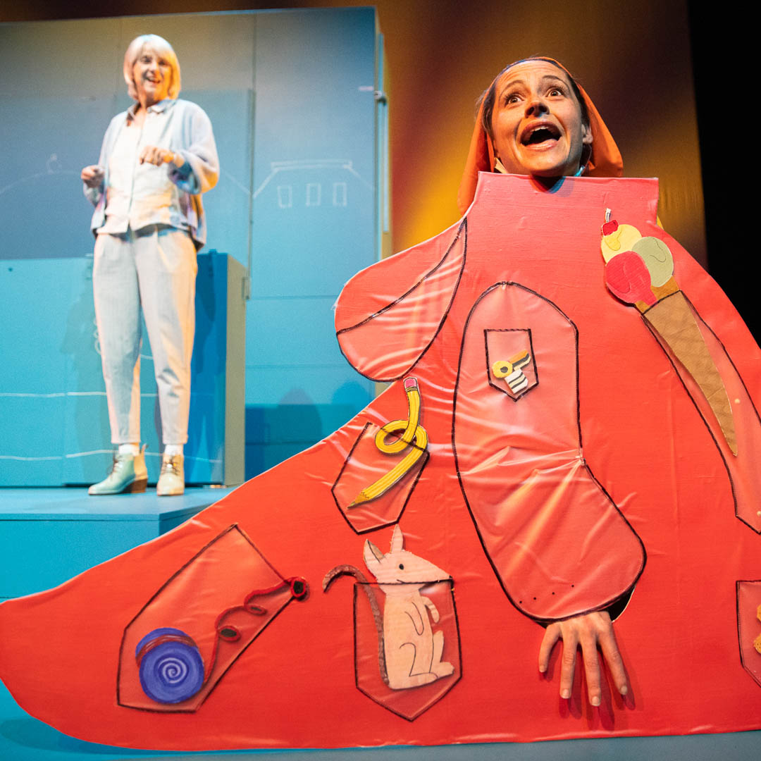 Heb je mijn zusje gezien? toont speelse voorstelling met groot rood kostuum en theatrale setting.