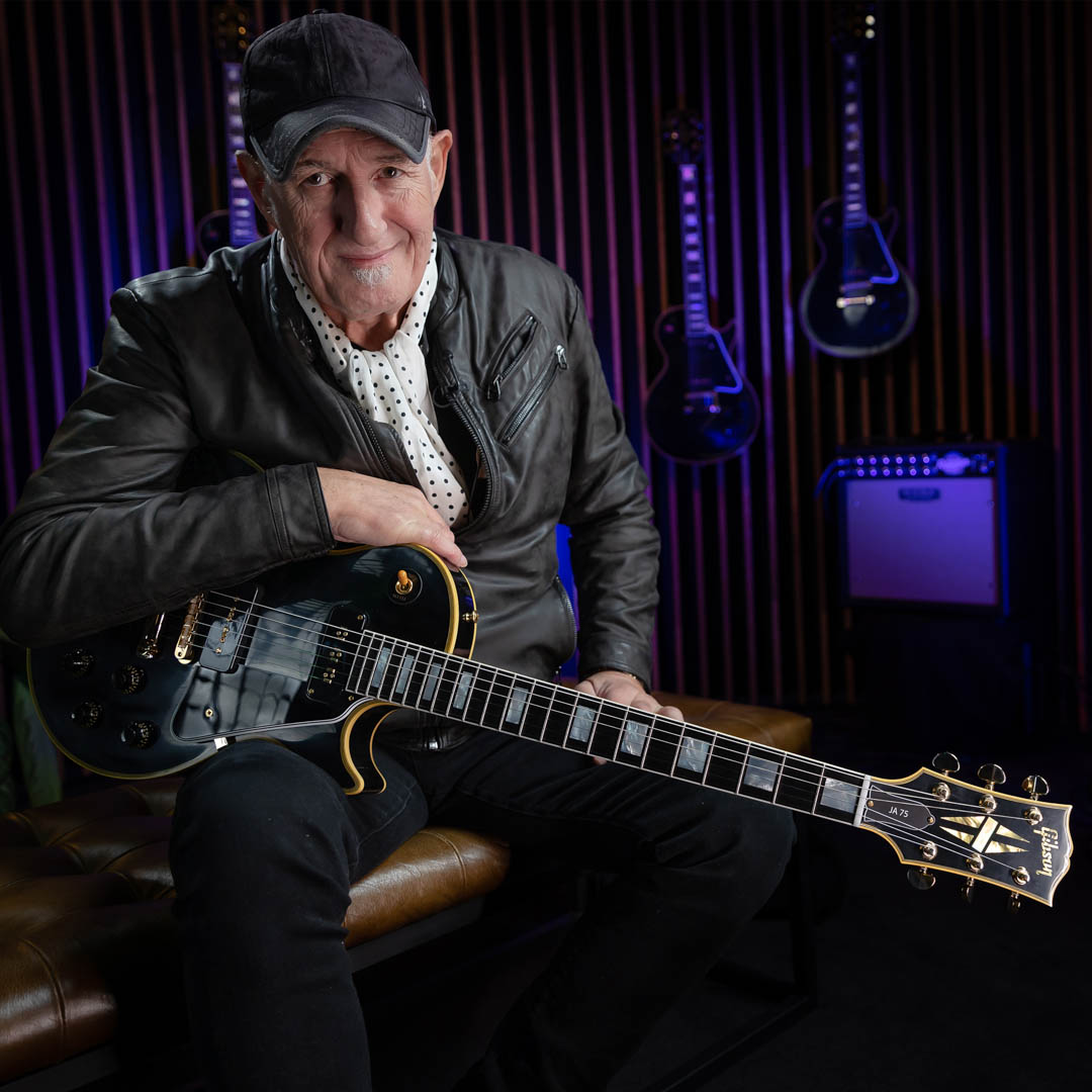 Jan Akkerman zit met gitaar in My Brainbox, My Focus onder paars podiumlicht.