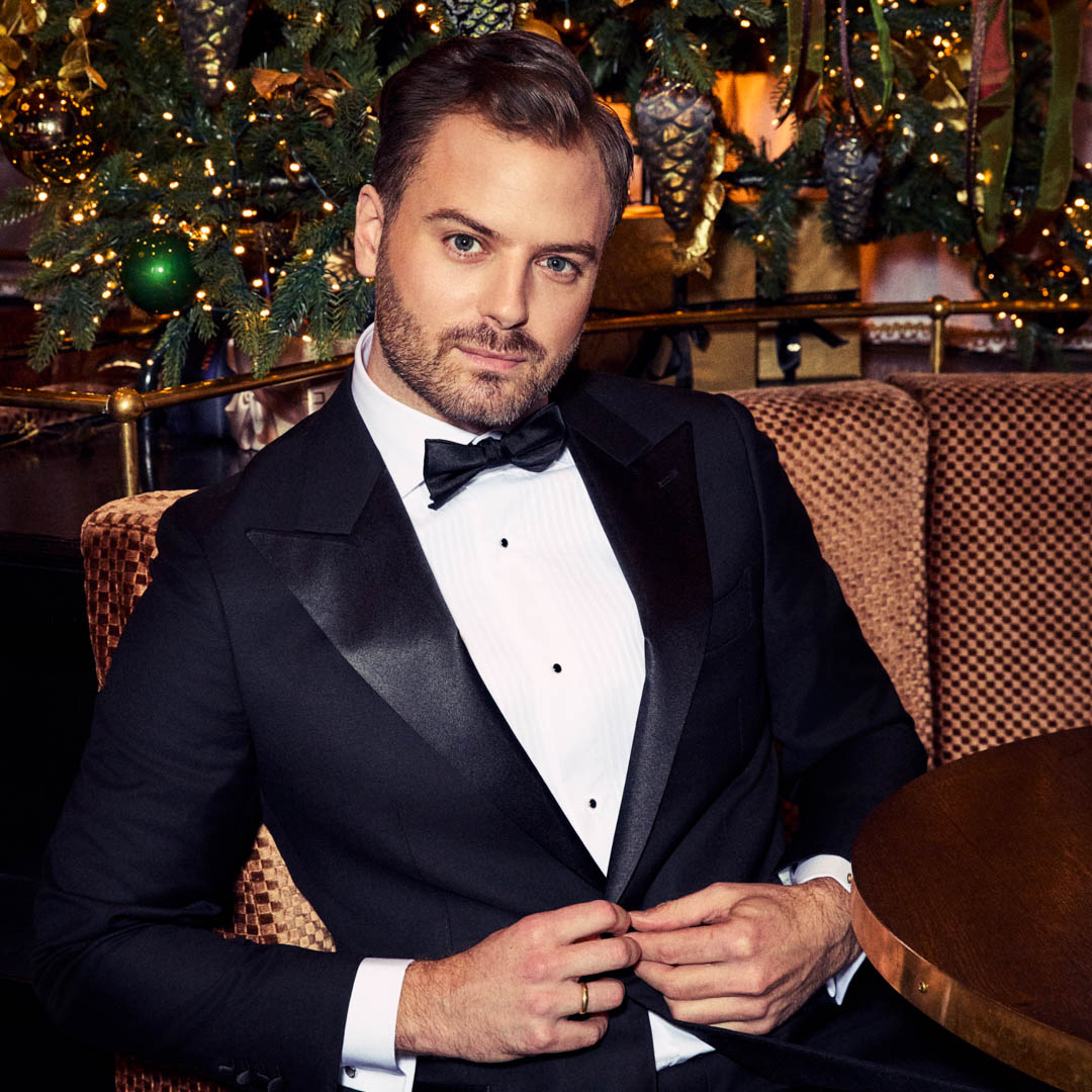 Jim Bakkum in smoking voor een kerstboom in de kerstshow Jim's Jingle Bells.