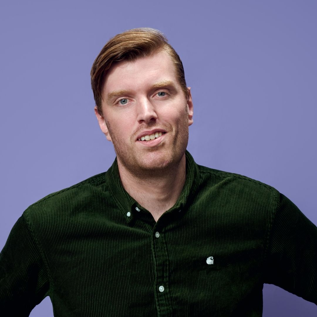 In €472.000 zie je Oscar Smit in groen overhemd tegen effen paarse achtergrond.