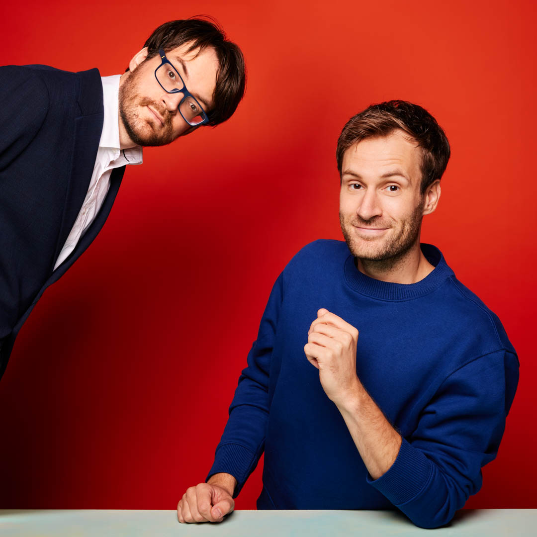 Roel en Jos Maalderink voor rode achtergrond in cabaretvoorstelling Verbroedering.