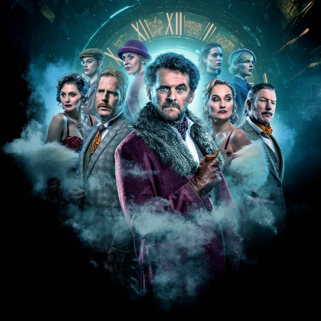 Groep acteurs in victoriaanse pakken en jurken omgeven door blauwe rook en theatraal licht.