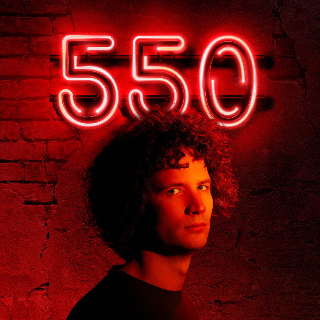 Tim Kroezen kijkt omhoog naar neon cijfers 550 in cabaretvoorstelling 550.