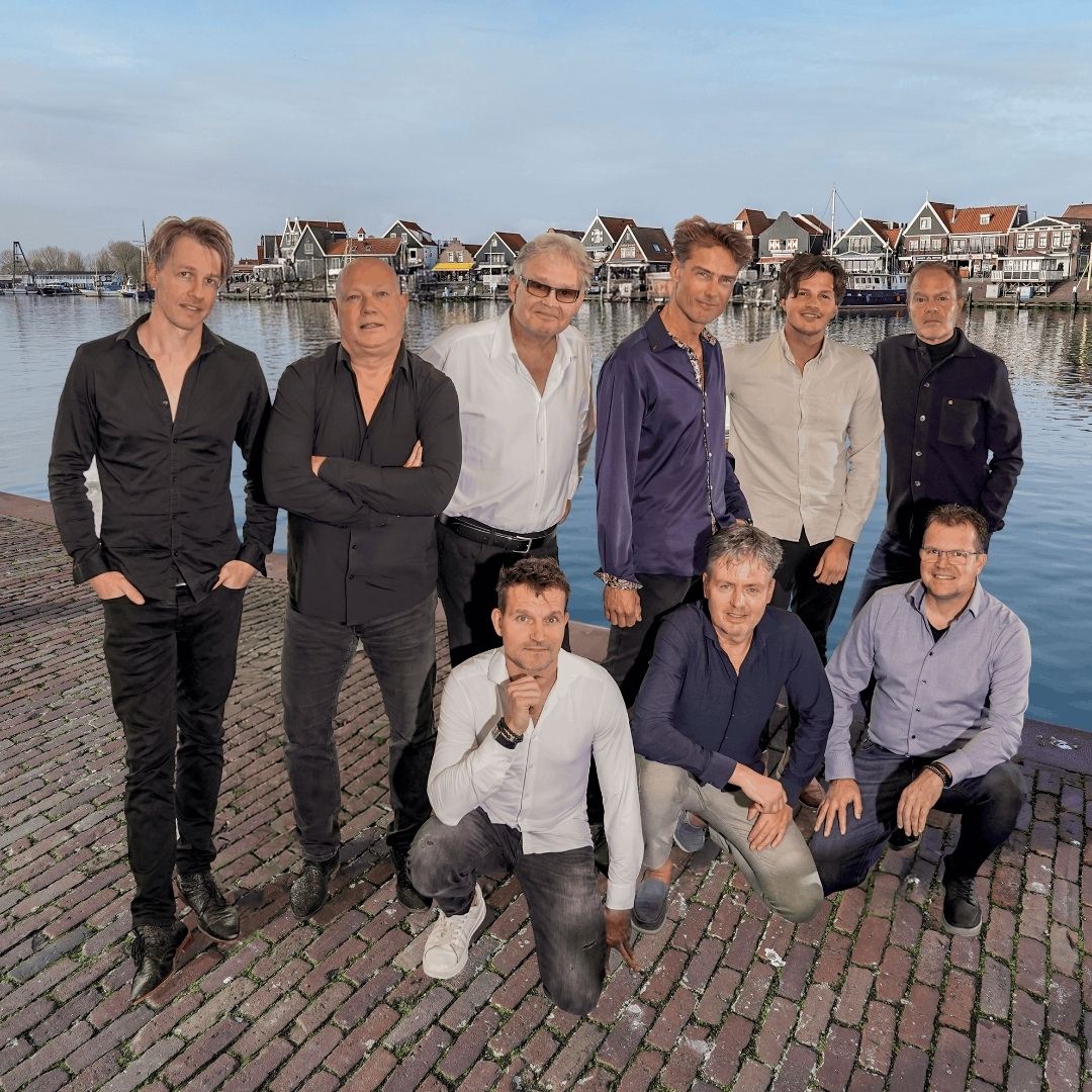 In Tribute to the Cats Band poseert de band op kade met haven en karakteristieke gevels.