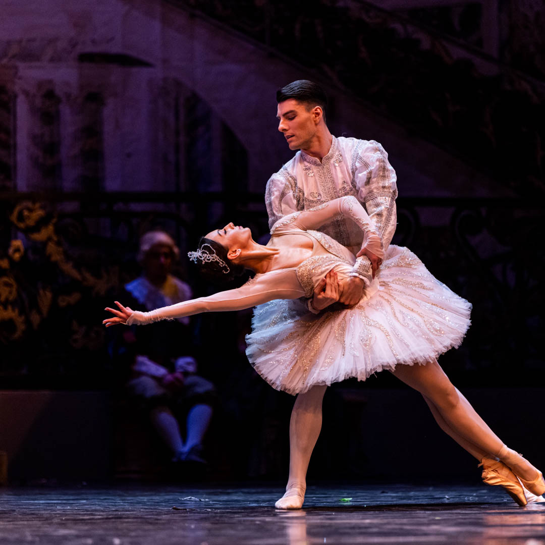Ballerina danst op spitzen in Zwanenmeer met sierlijke tutu onder zacht podiumlicht.