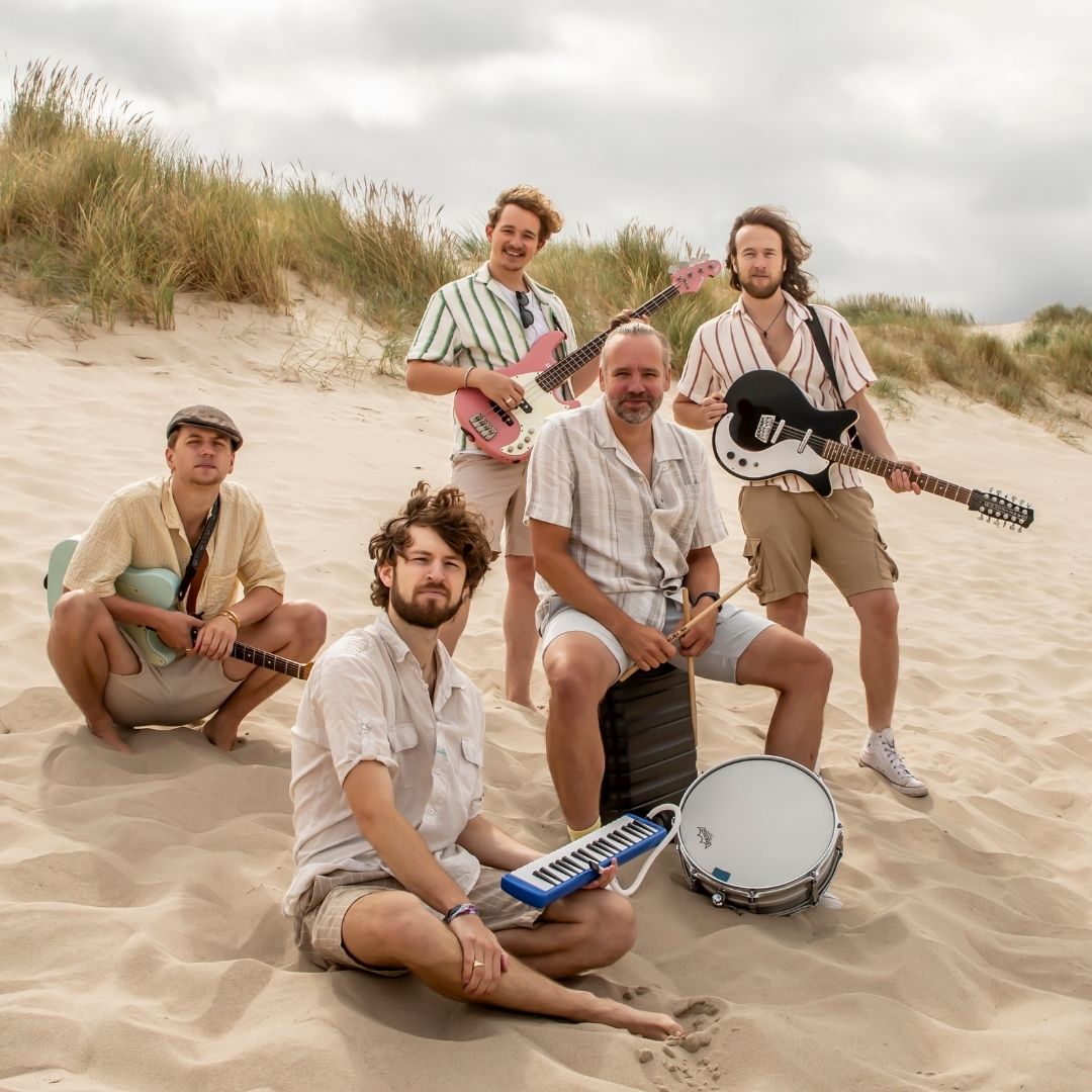 Bandleden van Beach Boys staan als een boyband op het strand
