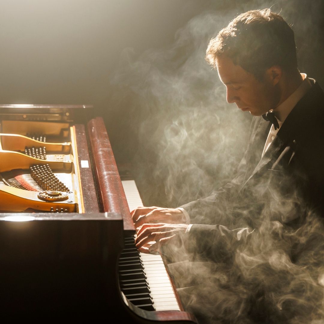 Wim Verschuren speelt piano in Klassieke Uurtje met rook en warm podiumlicht.